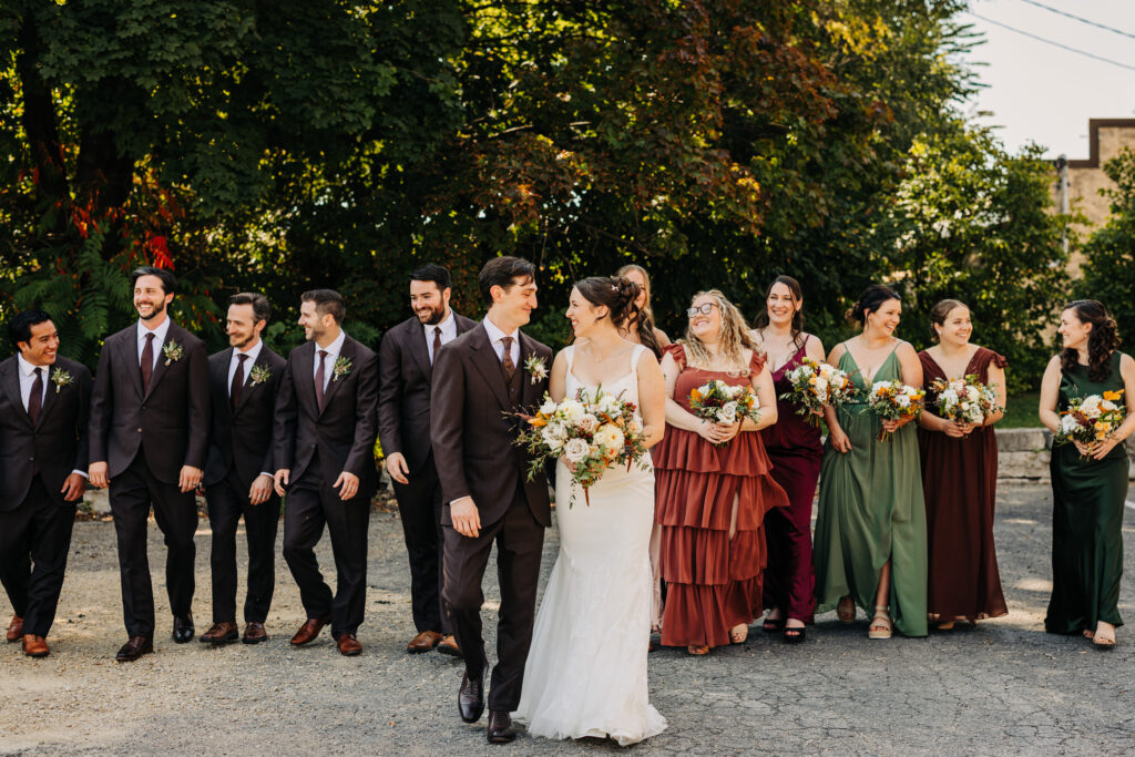 Bride and groom walking with their wedding party outdoors at The Lageret, dressed in coordinated fall wedding colors.