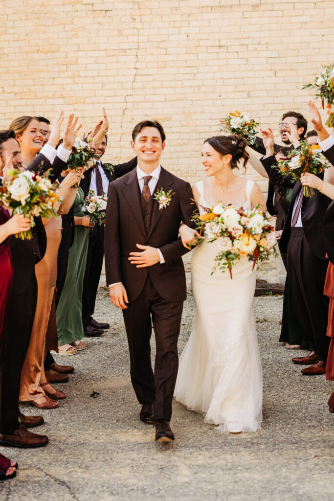 Close-up of bride and groom laughing as their wedding party celebrates around them during portraits at a Wisconsin wedding.