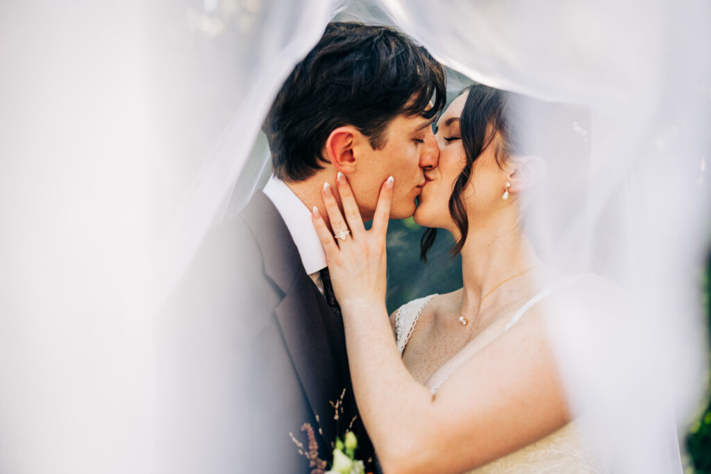 Bride and groom sharing a kiss under the veil during intimate wedding portraits at The Lageret.