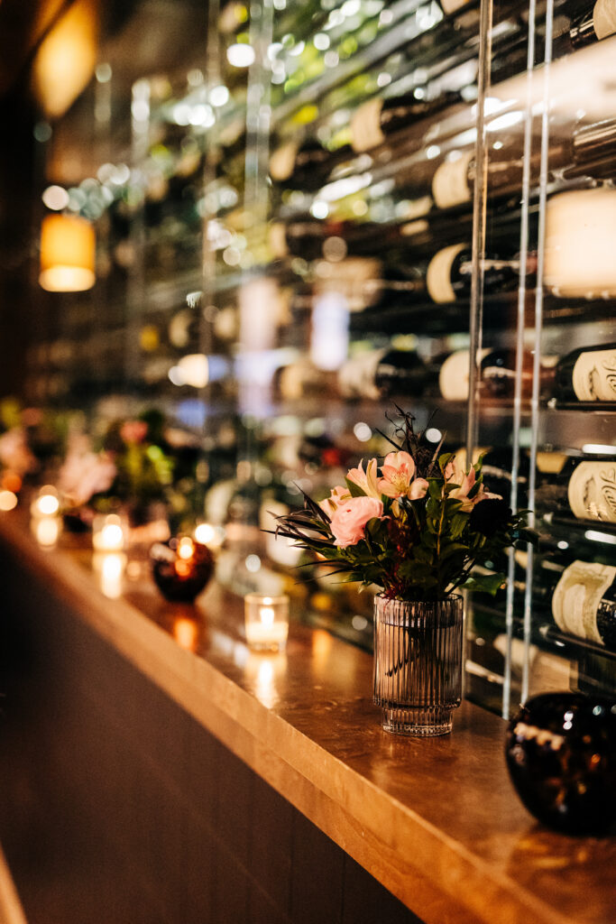 Wedding reception detail with floral arrangement and candles along bar at Edgewater wedding venue in Madison.