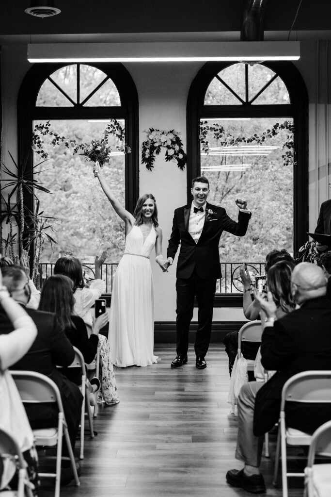 Bride and groom walking down aisle after ceremony at Ellsworth Block wedding in Madison as guests applaud and take photos.