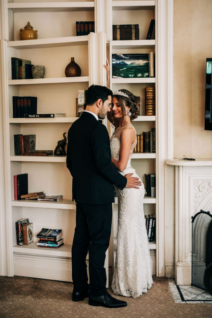 Bride and groom standing together in front of built-in bookshelves at Mansion Hill Inn wedding in Madison.