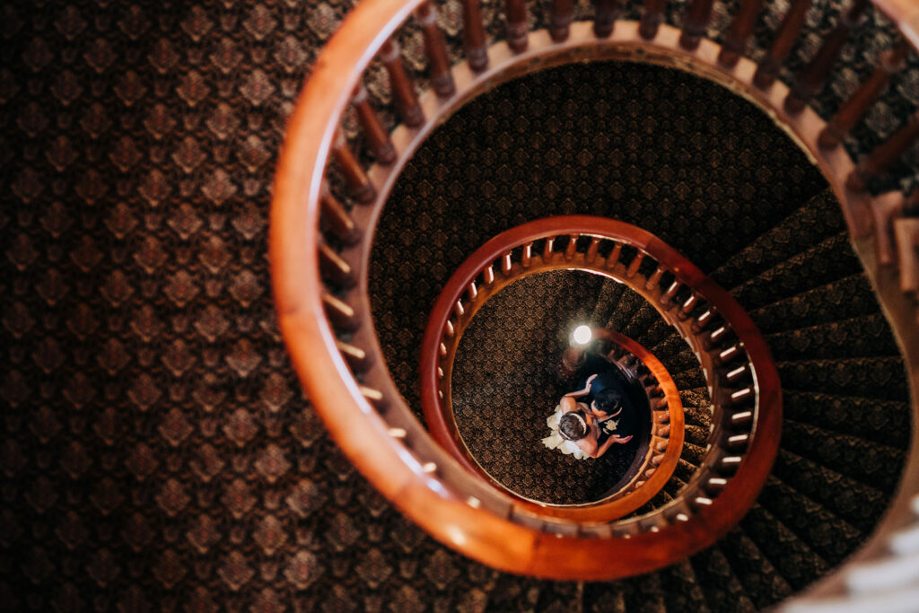 Overhead view of bride and groom embracing on spiral staircase at Mansion Hill Inn wedding venue in Madison.