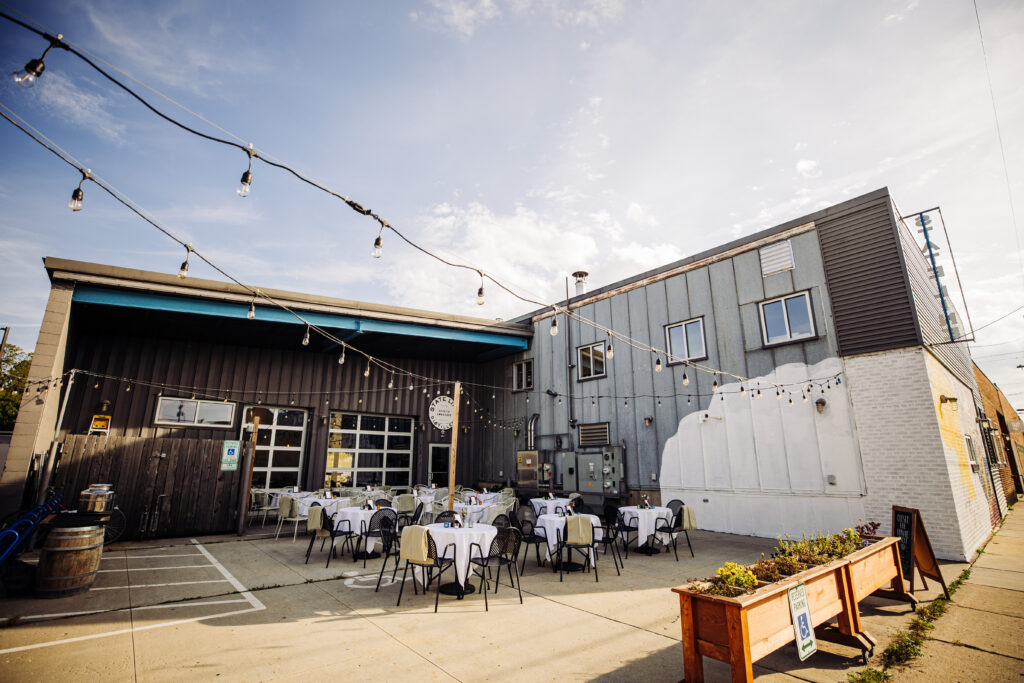Outdoor wedding reception setup at State Line Distillery in Madison with string lights and round tables in courtyard.