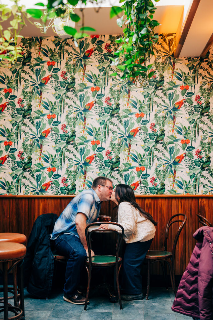 Couple kissing inside Leopold's Books Bar Caffè during their engagement session in Madison, Wisconsin.