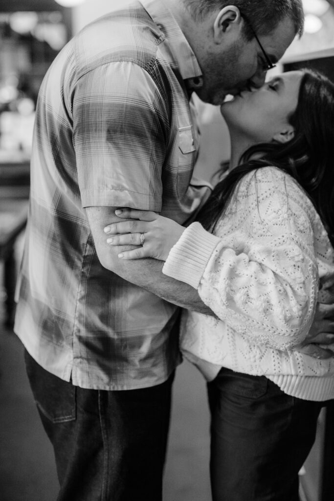 Couple kissing and holding arms at Leopold's Books Bar Caffè during Leopolds Madison engagement session in Madison, WI