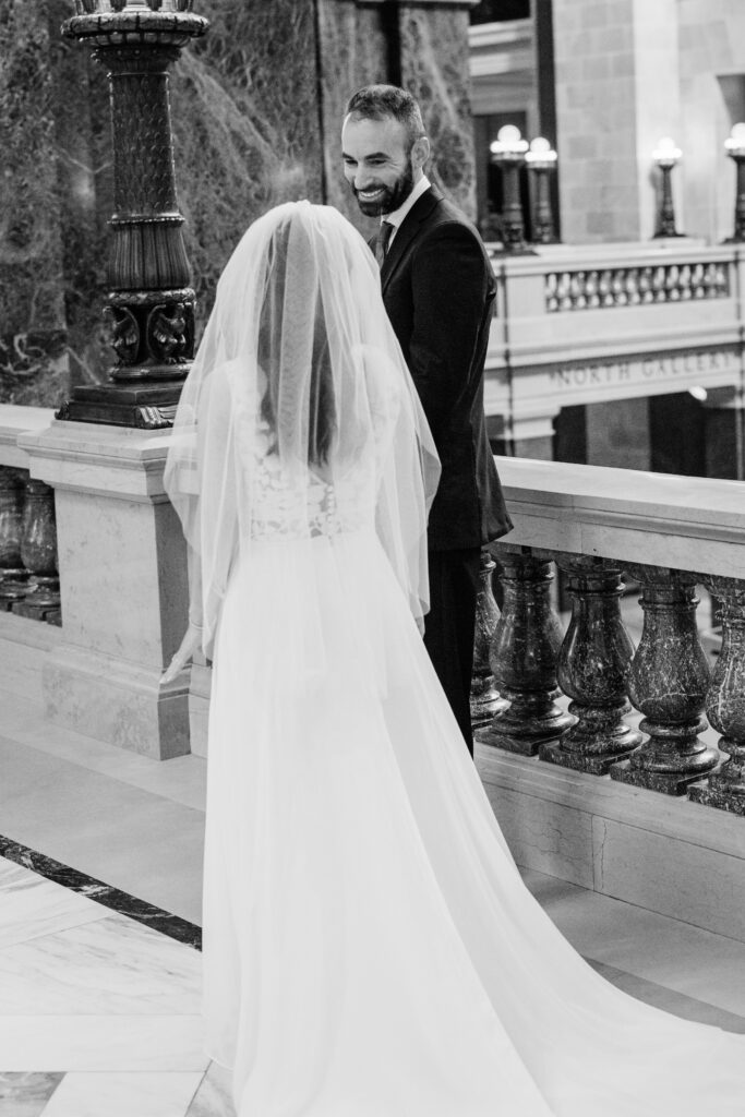Bride and groom sharing a quiet moment along the marble balcony inside the Wisconsin State Capitol in Madison.
