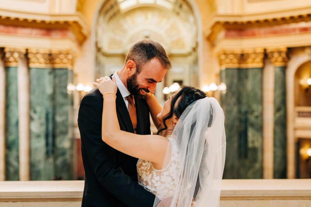 Newlywed couple embracing beneath the grand rotunda at the Wisconsin State Capitol wedding venue.