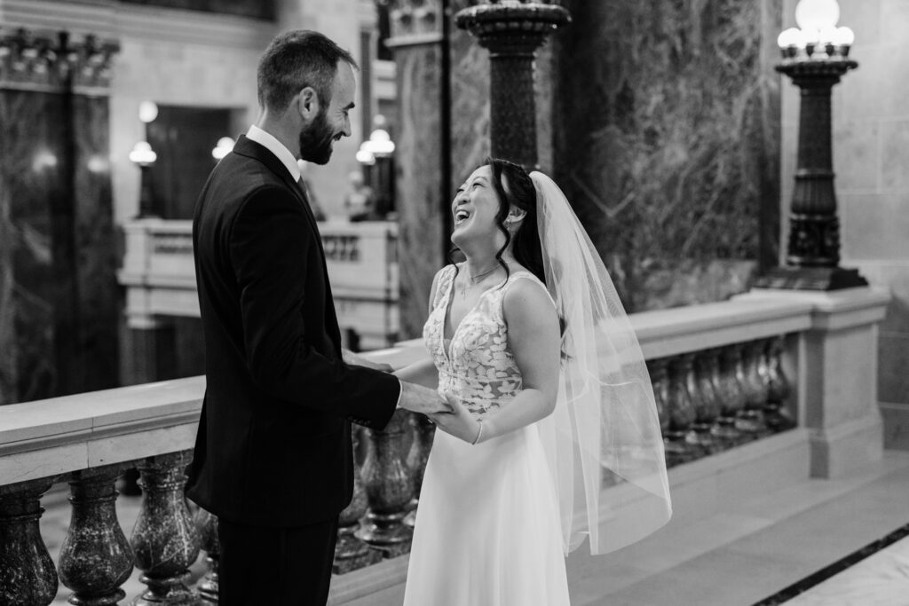 Bride and groom laughing together during romantic Capitol wedding portraits in downtown Madison, Wisconsin.