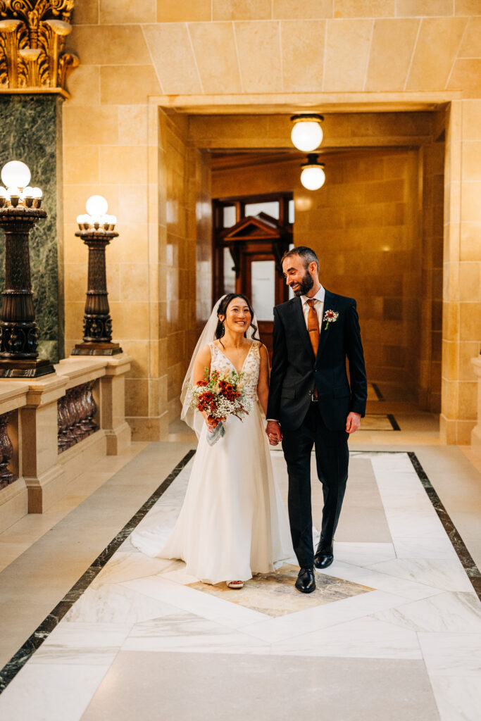 Newly married couple walking hand in hand through the ornate Wisconsin Capitol building in Madison.