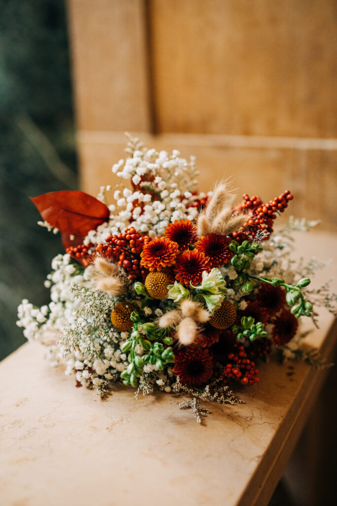 Autumn wedding bouquet with red florals, berries, and dried textures displayed inside the Wisconsin State Capitol.