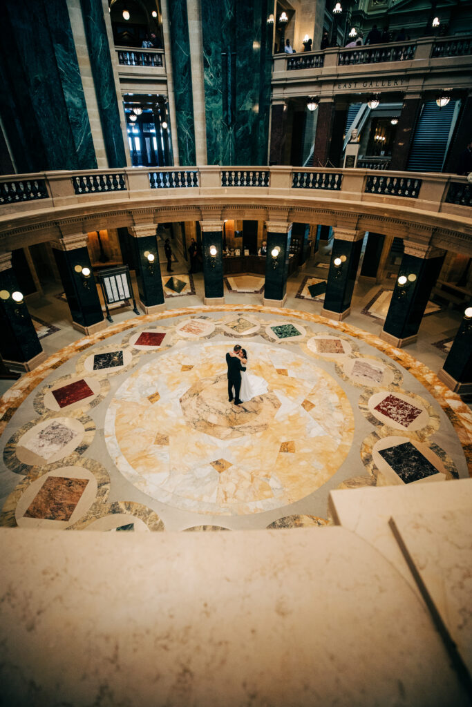 Overhead view of bride and groom embracing on the marble floor inside the Wisconsin State Capitol.
