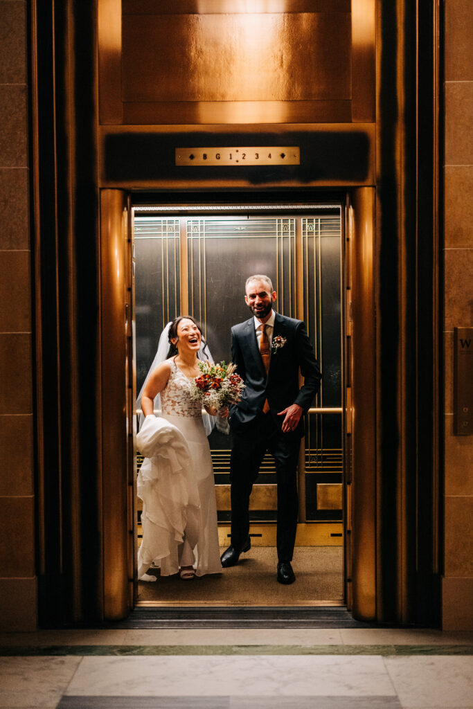 Bride and groom stepping out of a vintage Capitol elevator after wedding portraits in Madison, Wisconsin.
