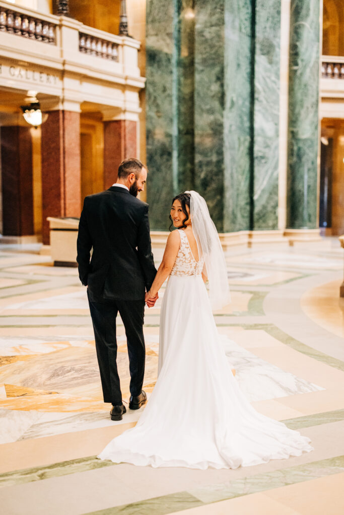 Bride and groom walking through the Wisconsin State Capitol rotunda after their Madison wedding ceremony.