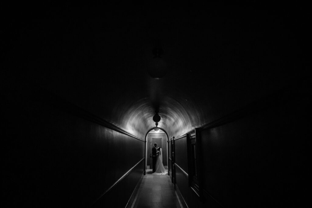 Moody black-and-white hallway portrait of bride and groom inside the Wisconsin State Capitol.