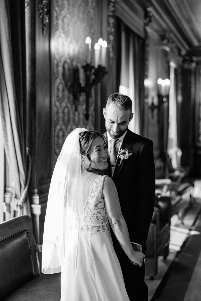Black-and-white bridal portrait of couple holding hands in ornate Wisconsin Capitol interior.