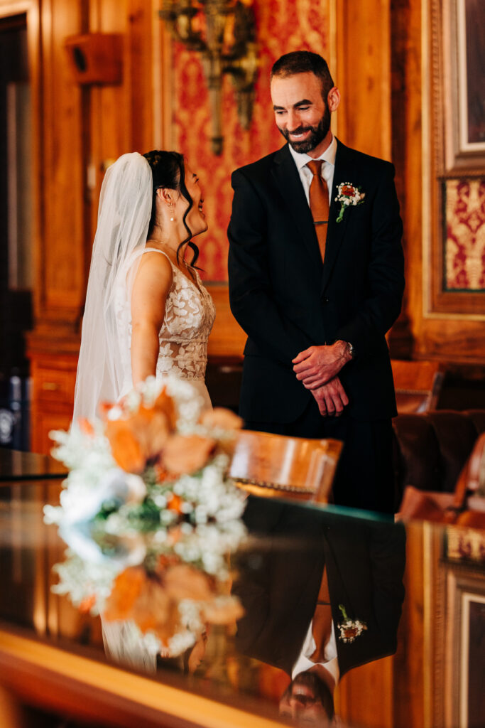 Bride and groom smiling together in richly decorated Capitol room during Wisconsin wedding portraits.