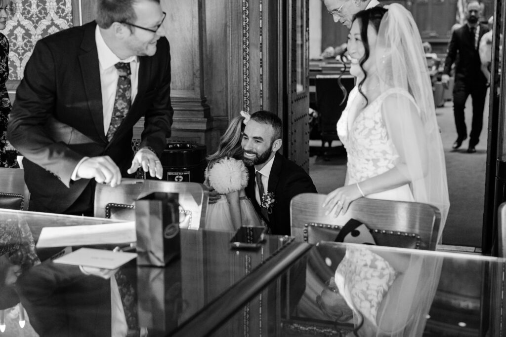 Bride and groom greeting a flower girl after their courthouse wedding ceremony inside a historic government building.