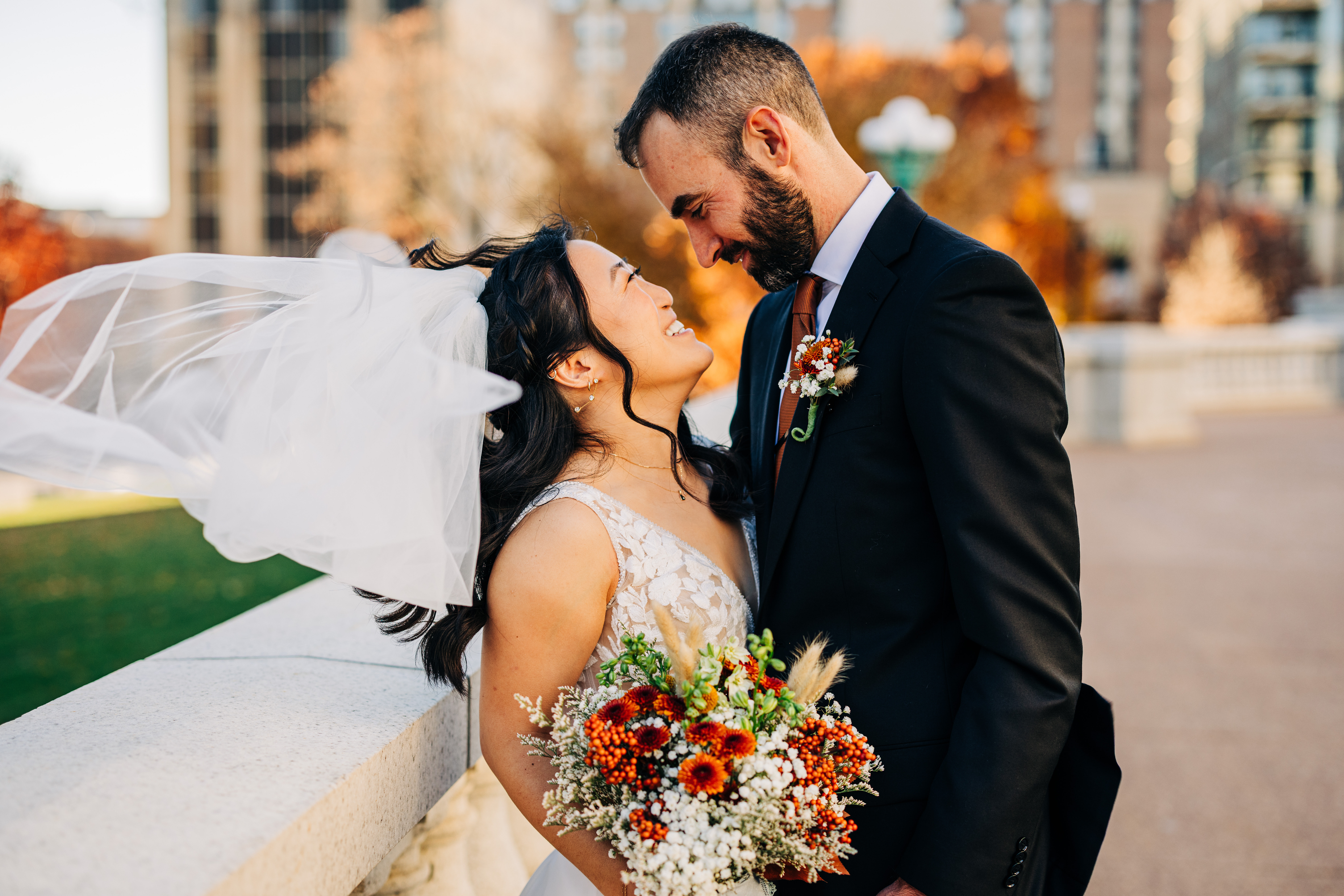 Bride smiling up at groom while holding a fall bouquet during golden hour courthouse wedding portraits.