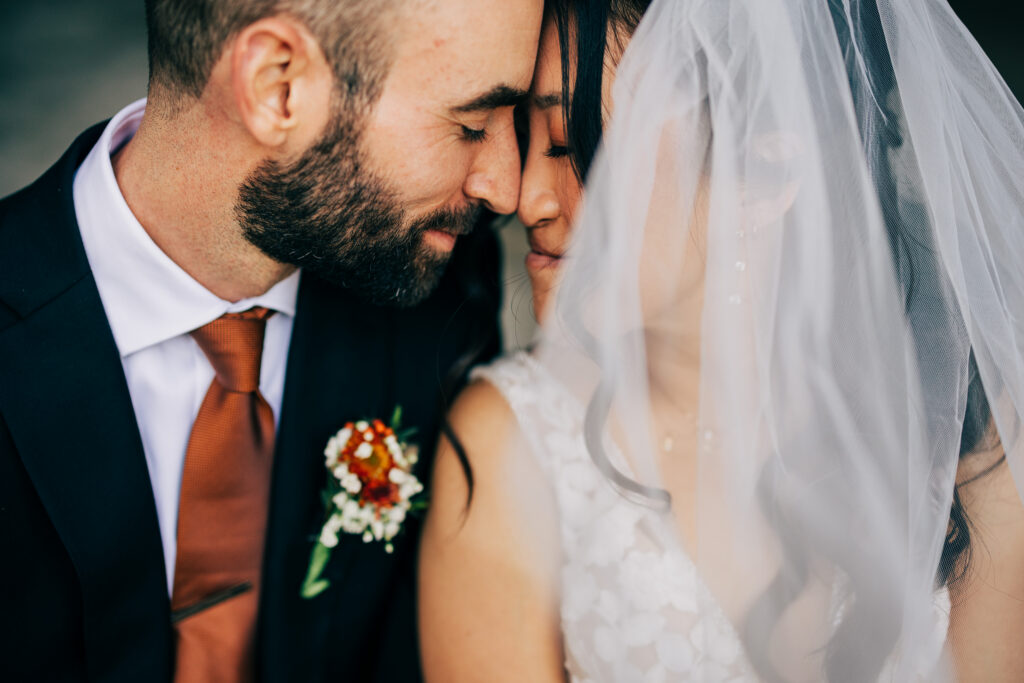 Close-up portrait of bride and groom beneath a soft wedding veil during intimate courthouse wedding portraits.