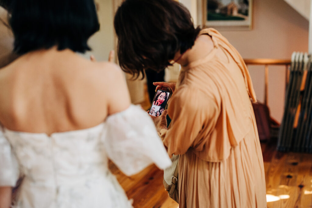 Guest showing a video call on a smartphone to the bride before the ceremony.