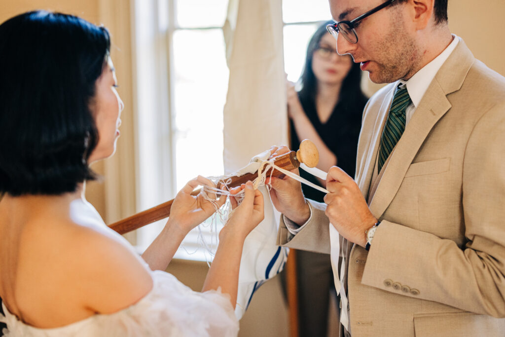 Couple preparing ceremonial ribbons beneath a wedding canopy during the ceremony.