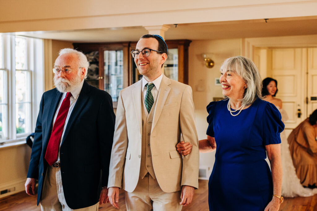 Groom walking arm in arm with family members before the ceremony begins.