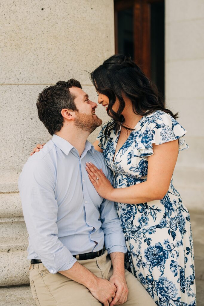 Close-up of the couple smiling at one another while embracing beside a Capitol column.