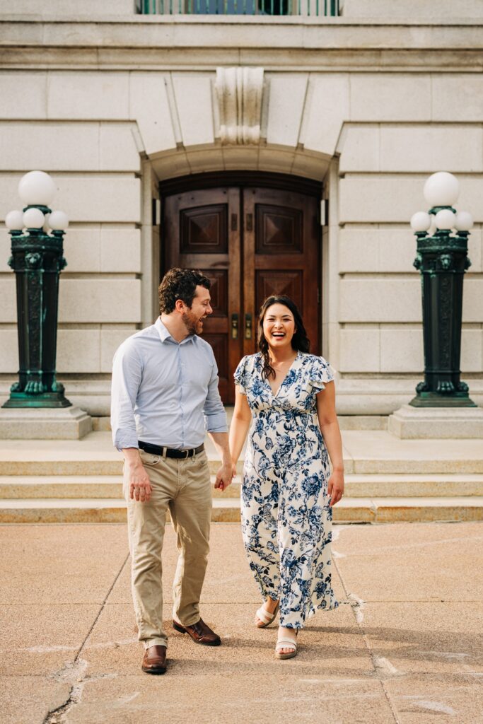 Couple laughing while walking hand in hand outside the Wisconsin State Capitol in downtown Madison.