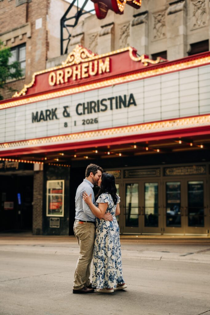 Engaged couple kissing in front of the Orpheum Theatre marquee during their downtown engagement session.